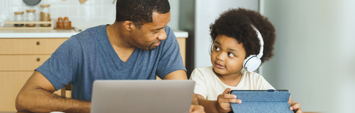 A father guides his child with virtual learning.